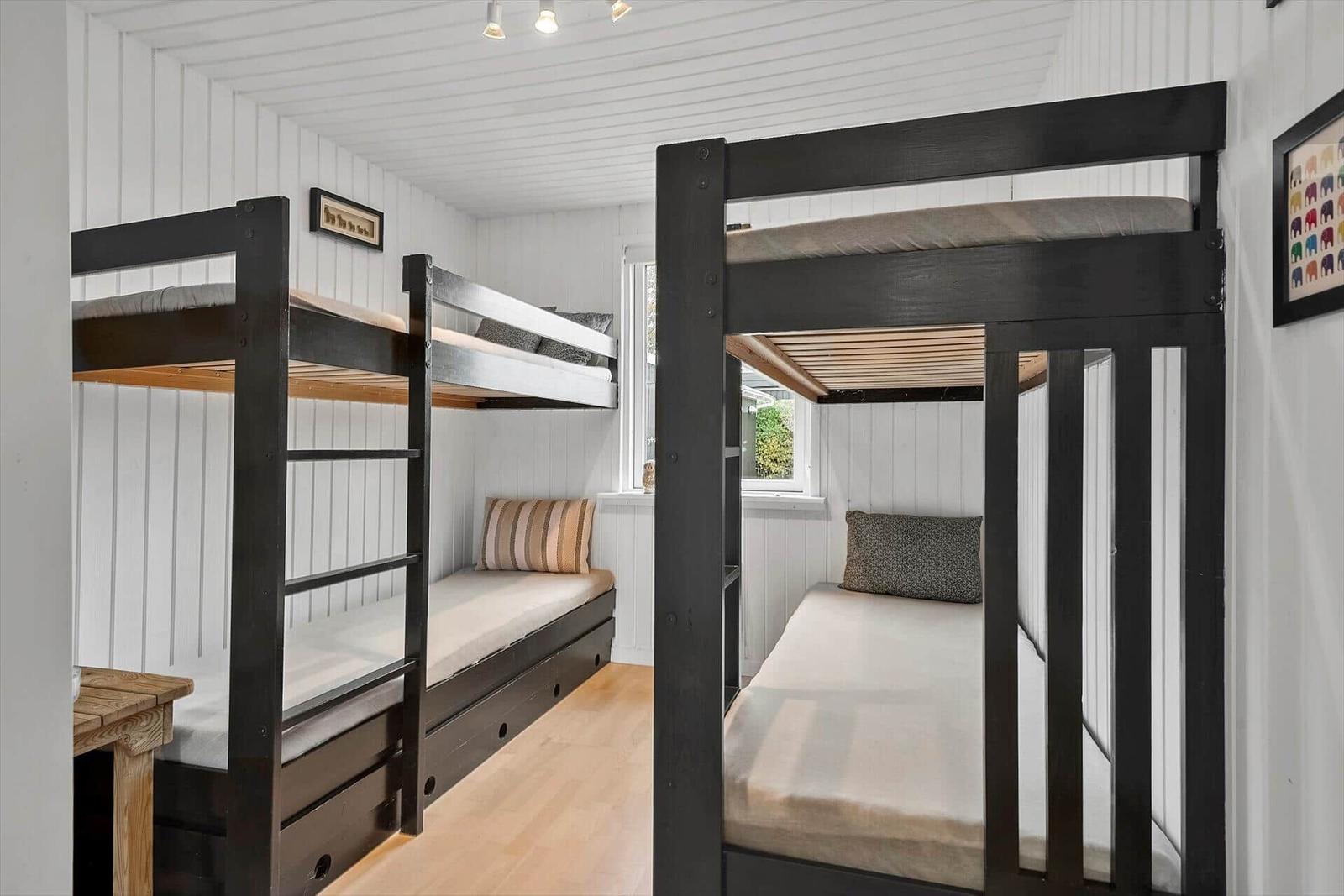 Zimmer mit zwei Stockbetten und Holzboden. Fenster und Wanddekoration sichtbar.