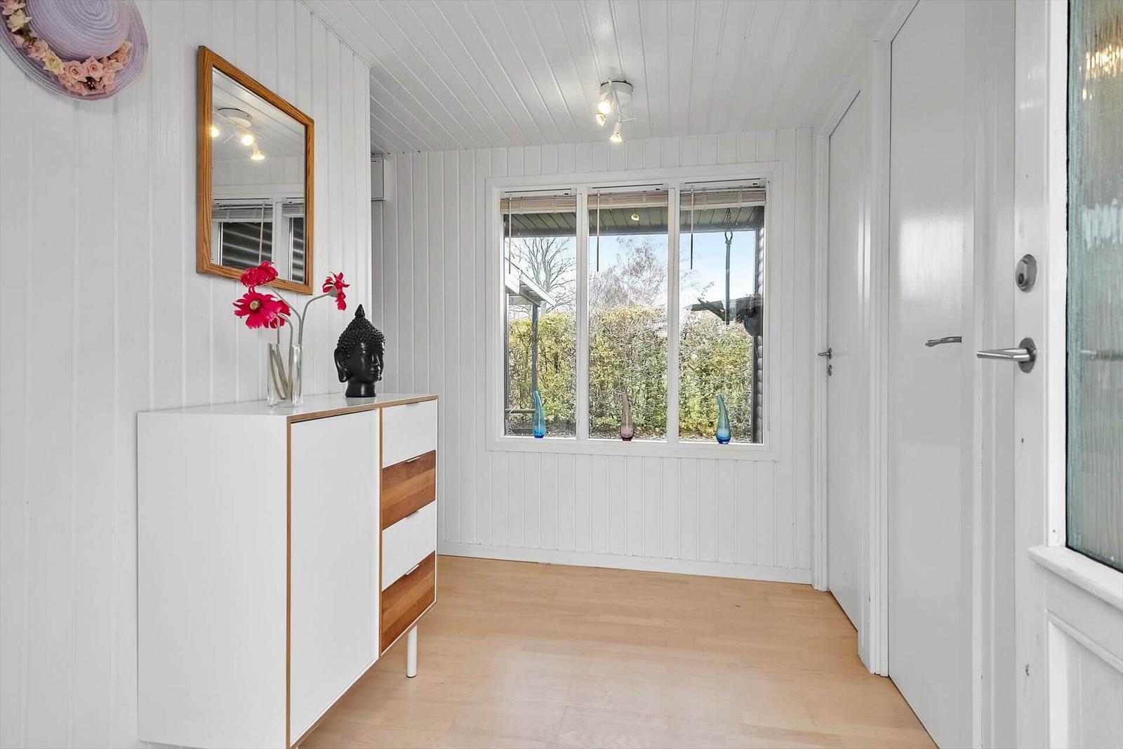 Eingangsbereich mit Schrank, Spiegel und Fenster zum Garten.
