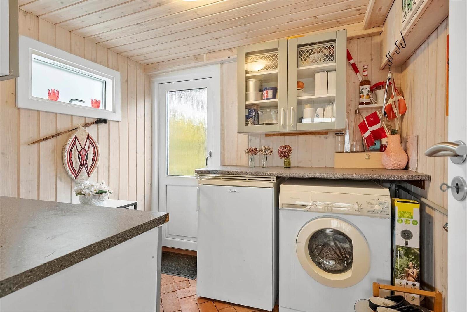 Küche mit Waschmaschine, Kühlschrank und Holzwänden.