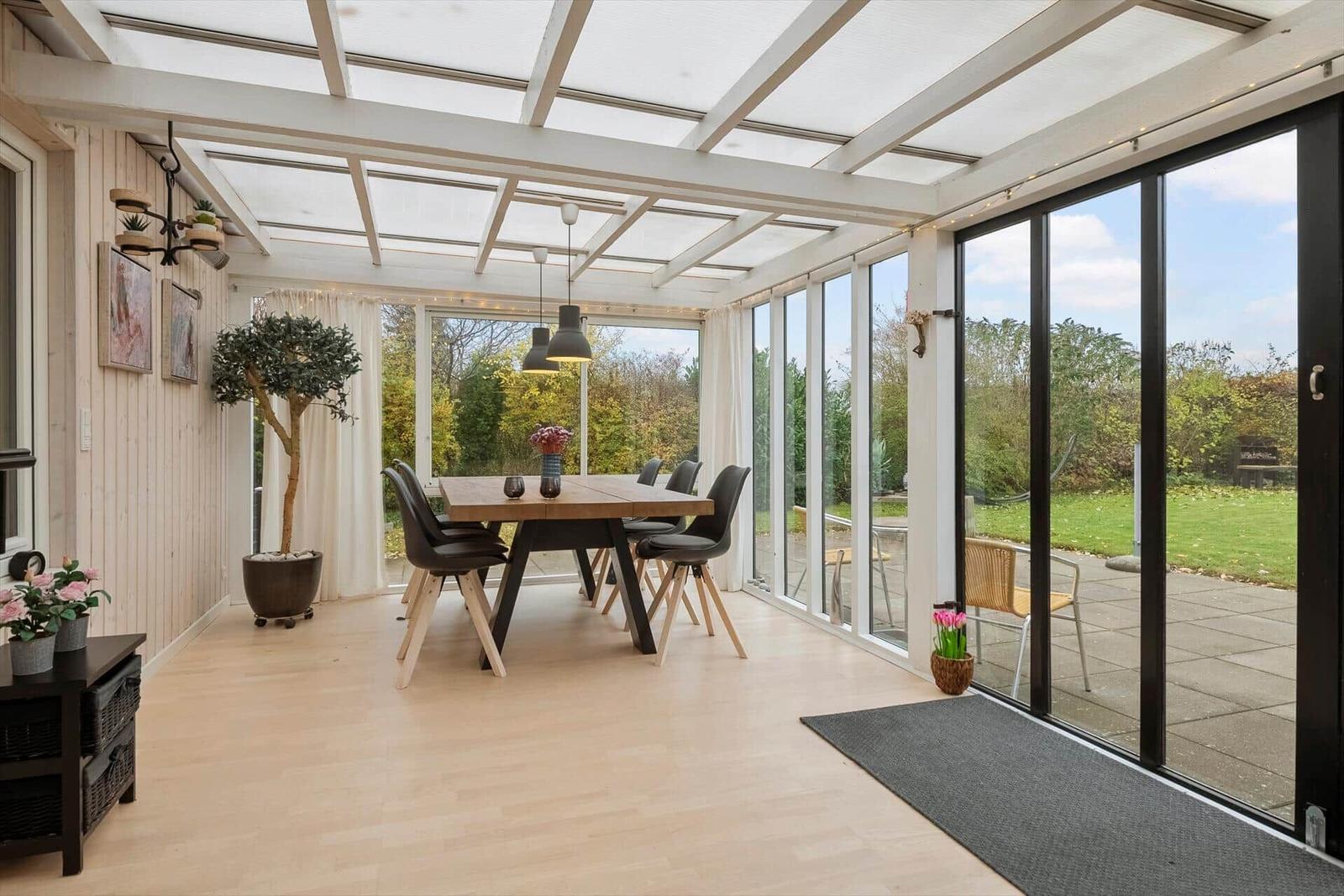 Dining room with glass roof and large windows overlooking garden