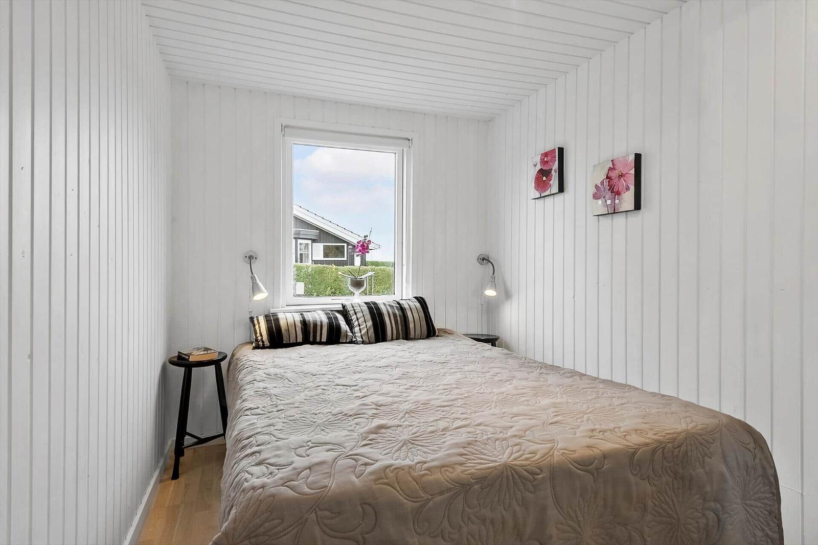 Schlafzimmer mit Bett, Fenster und Wandbildern.