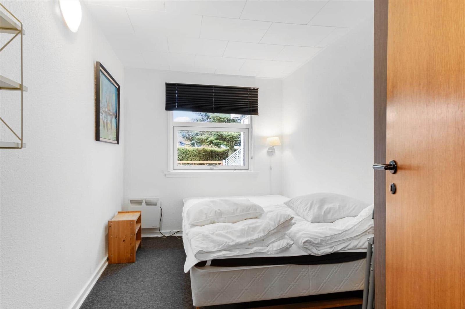 Schlafzimmer mit Bett, Fenster und Holzmöbel.