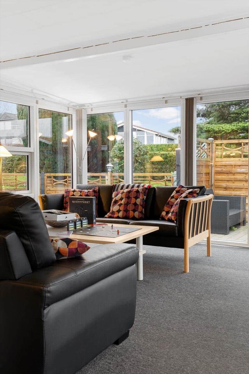 Wohnzimmer mit Sofa, Couchtisch und großen Fenstern zur Außenterrasse.