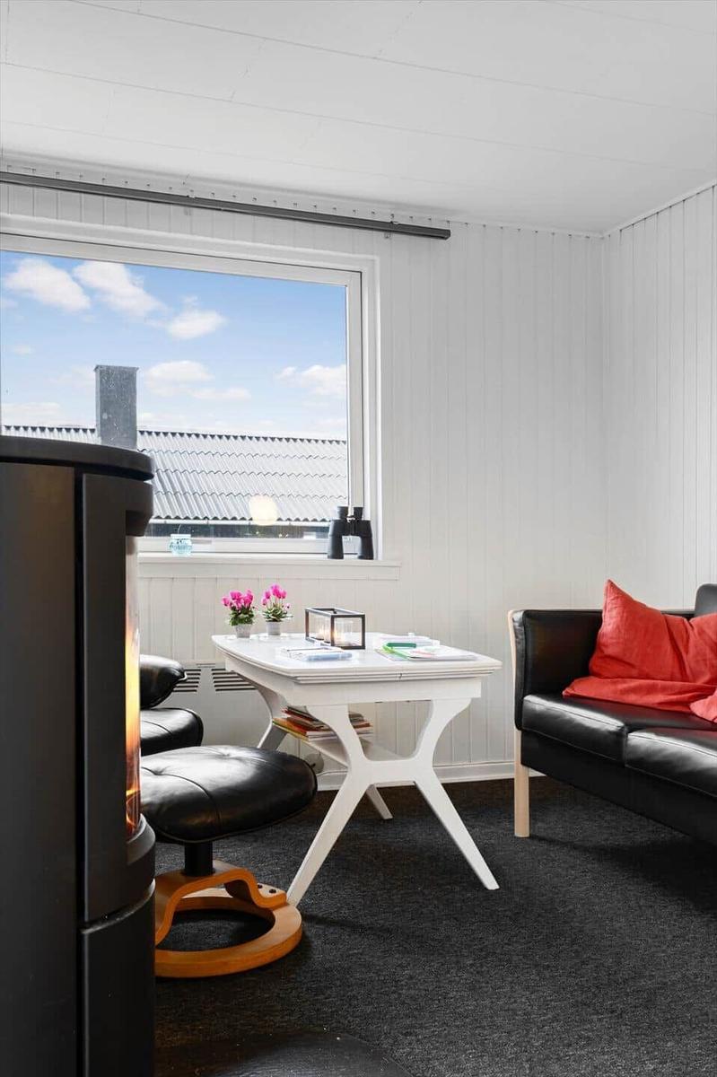 Raum mit Sofa, Tisch und Kamin, großes Fenster mit Blick auf Dach.
