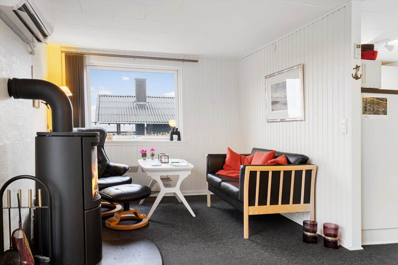 Wohnraum mit Kamin, Sofa und Sitzgelegenheit. Fenster zeigt Dach und Himmel.