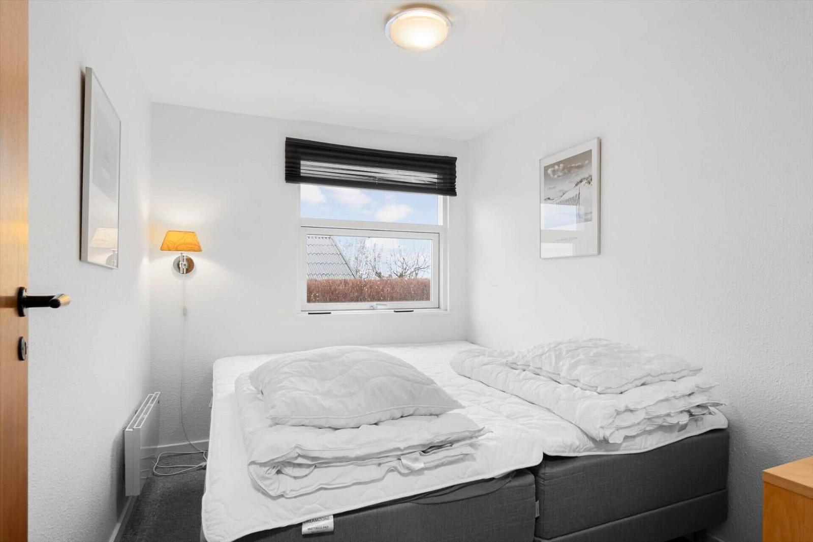 Schlafzimmer mit Doppelbett, Fenster und Wandlampen.