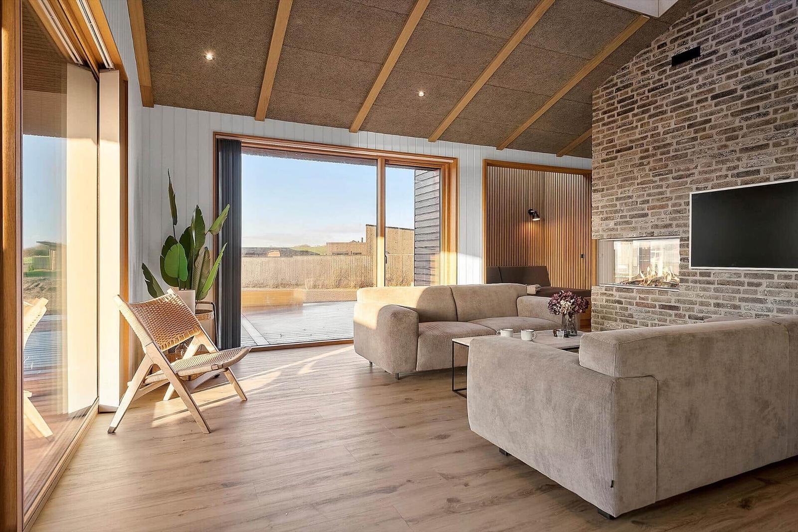 Wohnzimmer mit Sofa, Kamin und großem Fenster zur Aussicht.