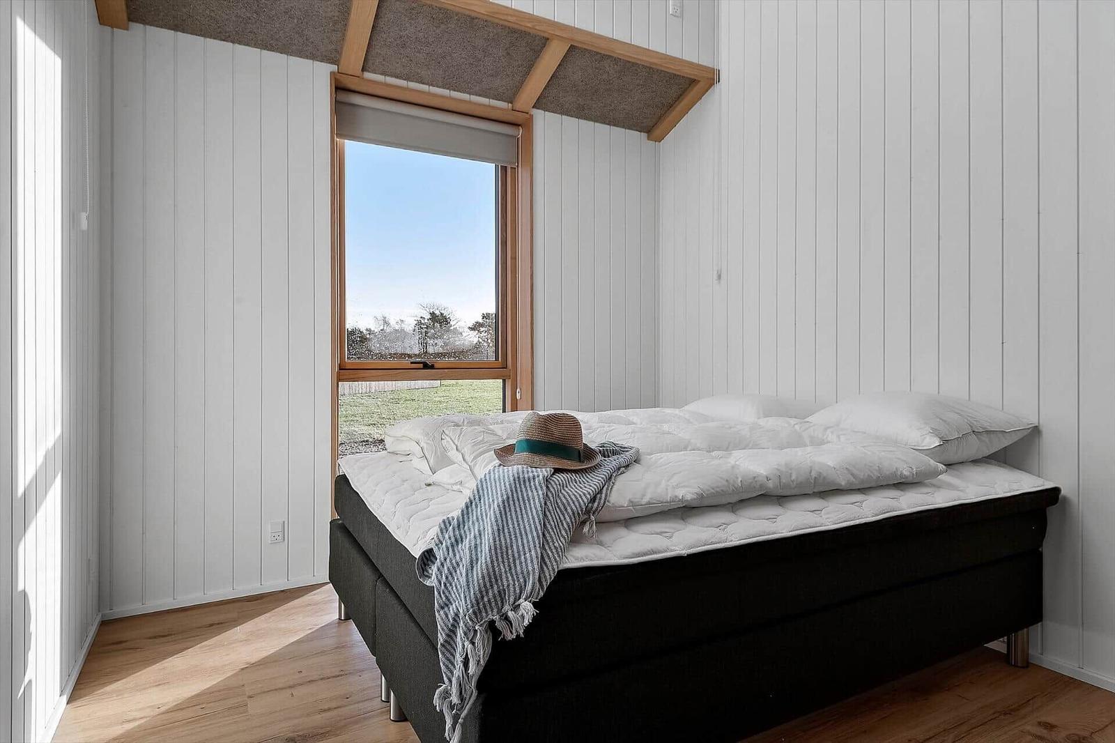 Schlafzimmer mit Bett, Fenster und Holzboden.