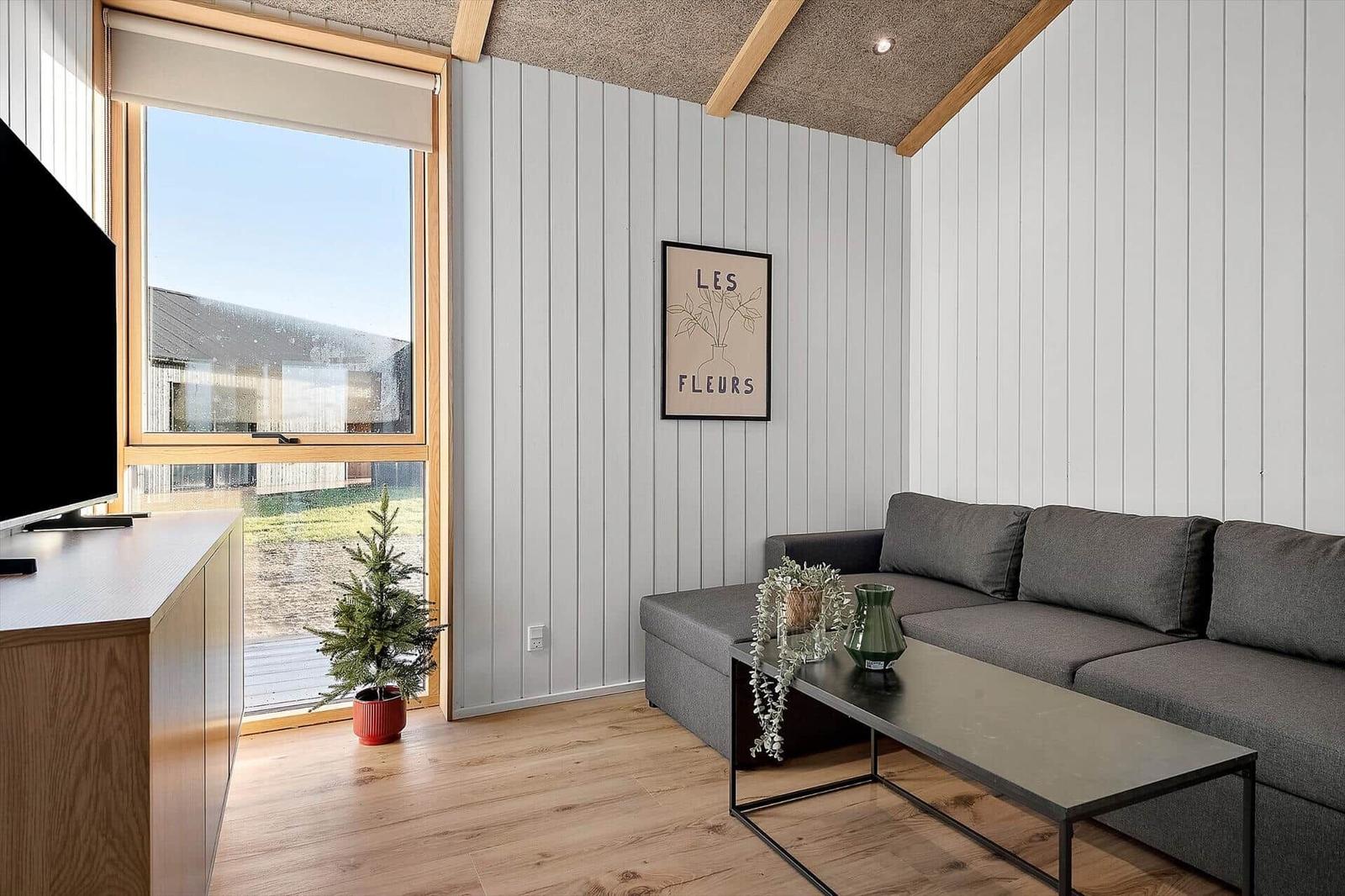 Wohnzimmer mit Sofa, Couchtisch und Fenster zur Außenseite.