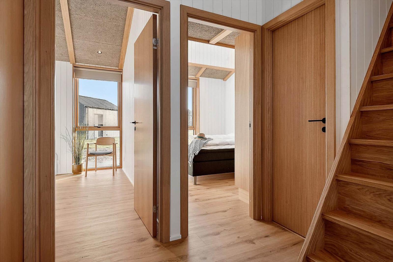 Holzgetäfelte Wände und Türen. Blick in Schlafzimmer und Wohnbereich mit Fenster und Stuhl.