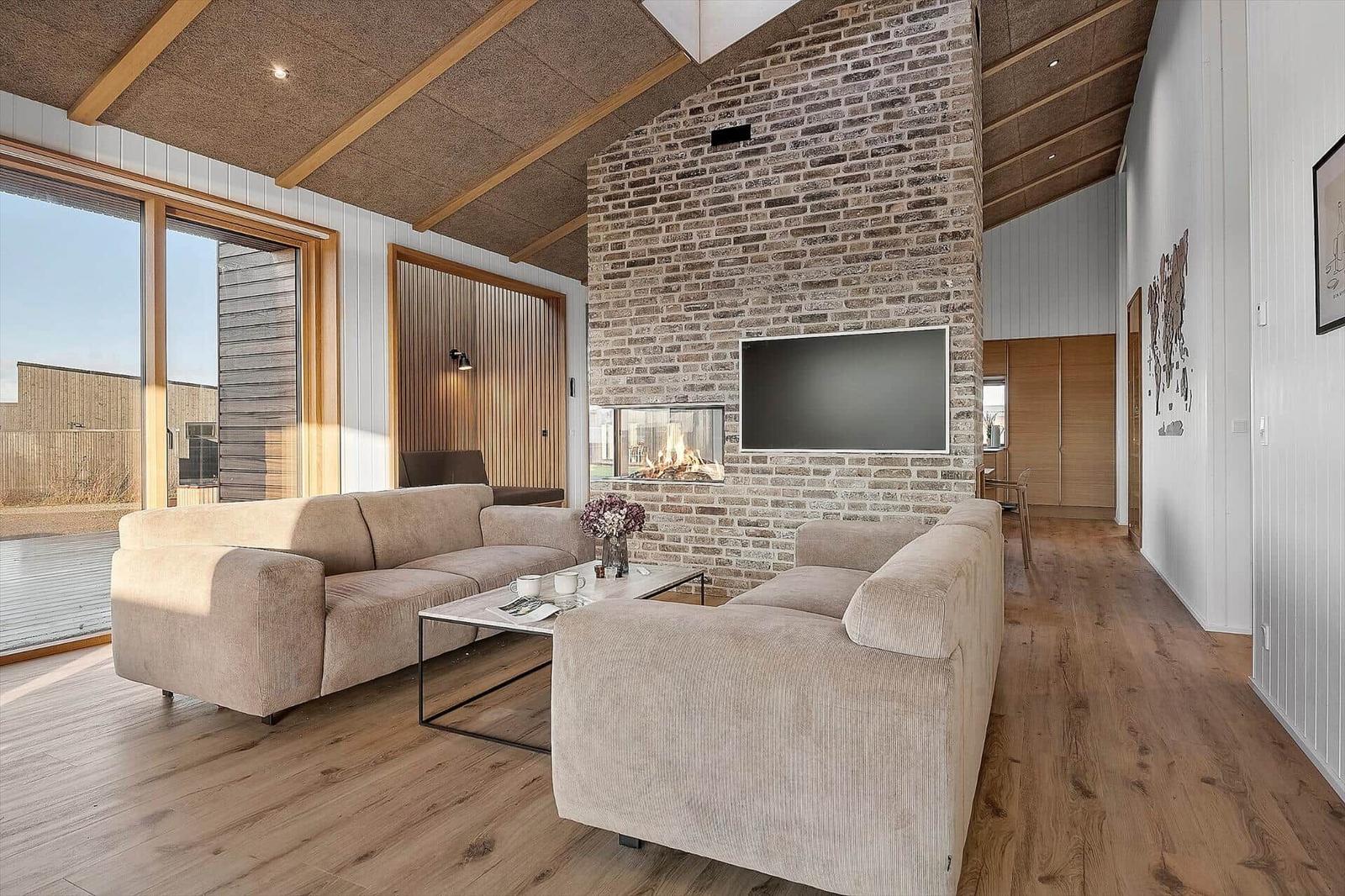 Wohnzimmer mit Sofa, Kamin und Fernseher an Steinwand