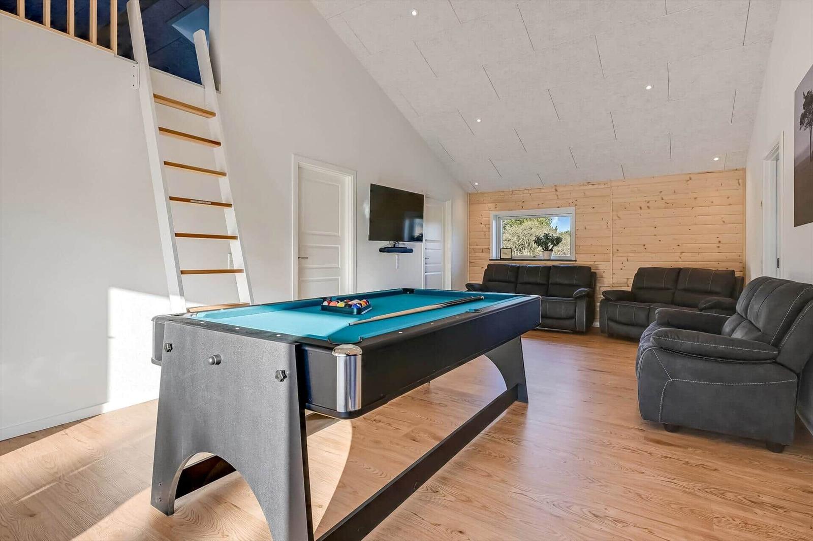 Pool table with blue felt, gray chairs, and wooden wall in living area.