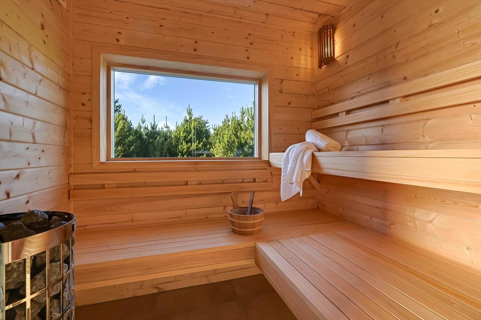 Sauna with wooden bench, window and bucket