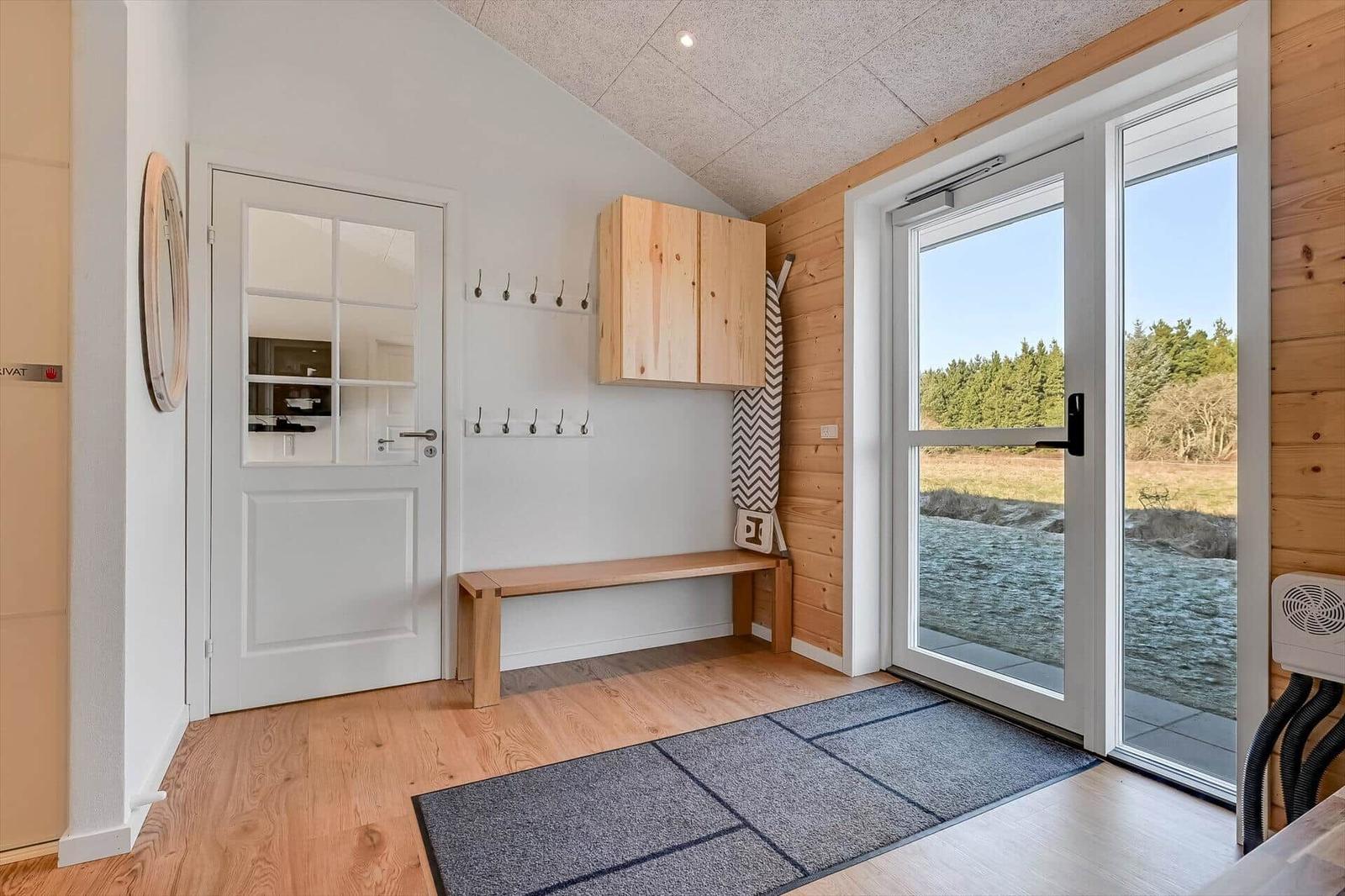 Entrance with wooden bench, coat rack, and view of river.