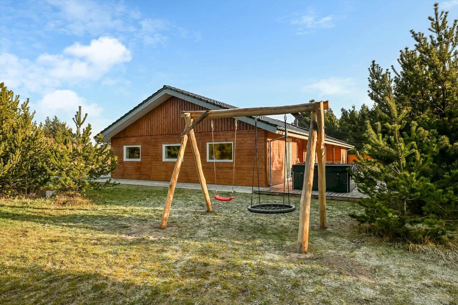 Wooden cabin with playground and hot tub in the garden