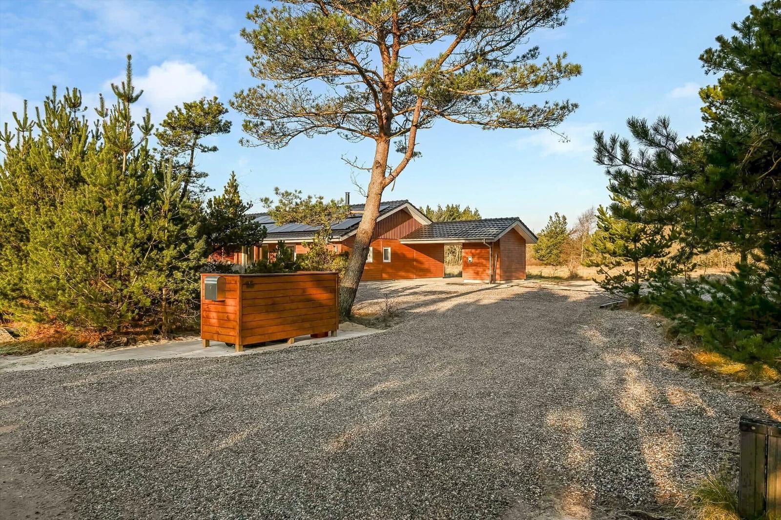 Wooden house with roof and gravel path among trees
