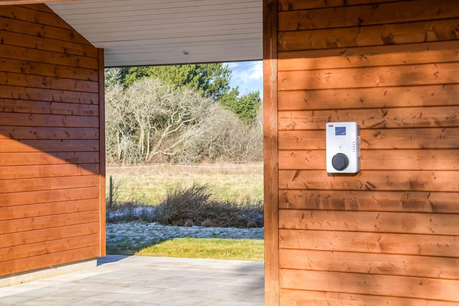 House with wooden wall and view of meadow and trees.