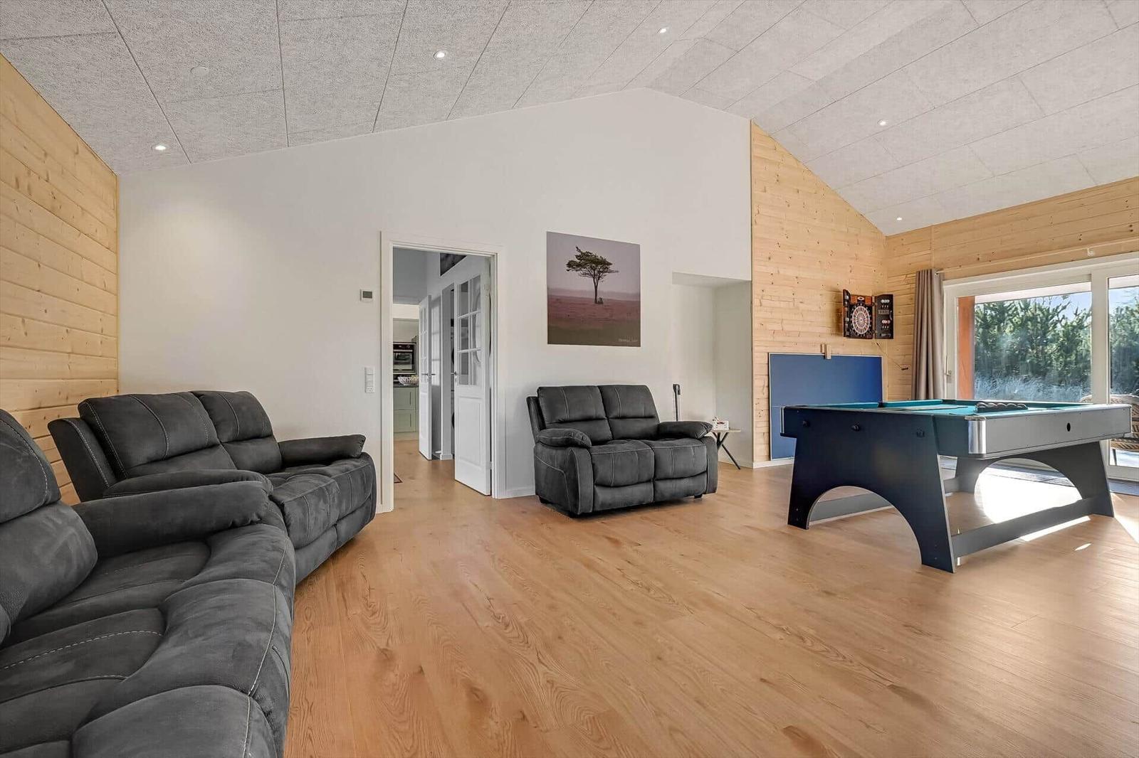 Large living room with pool table, sofa, and wood wall