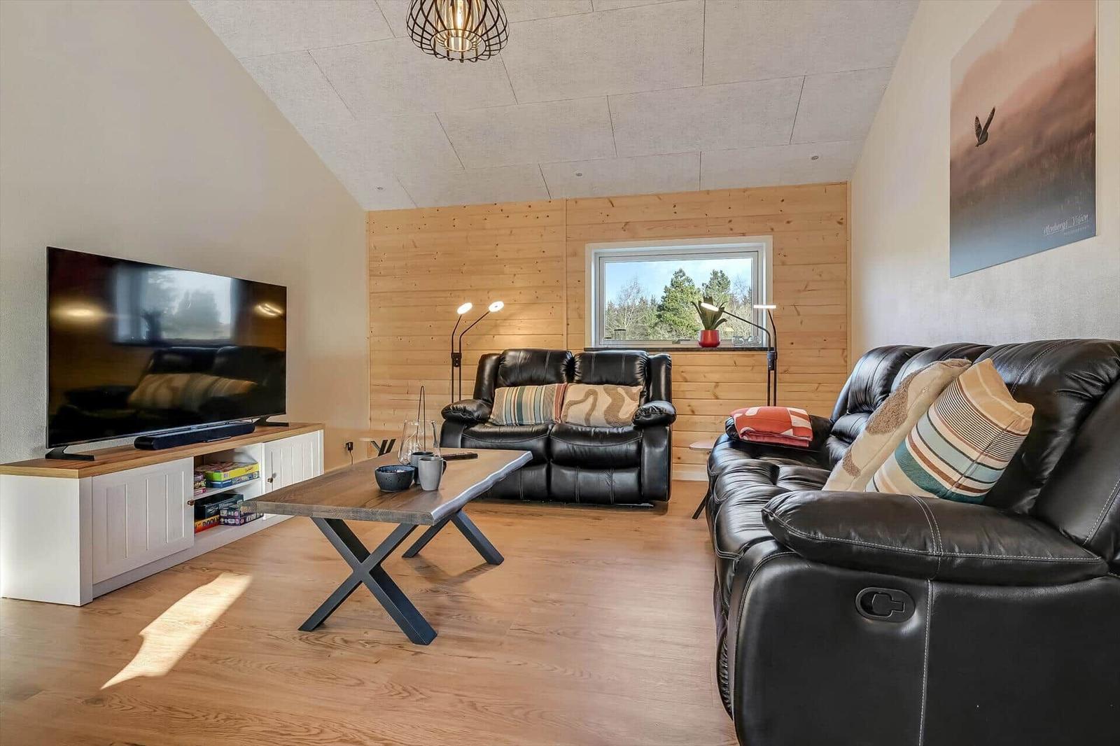 Living room with leather sofa, TV, and wood wall
