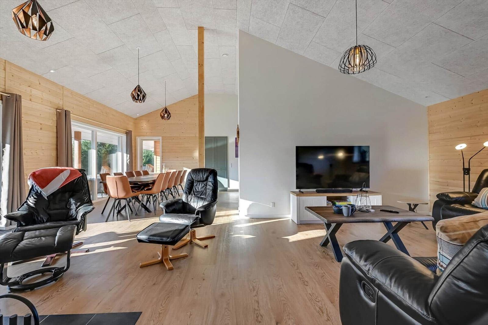 Living and dining area with leather sofas, TV, and wooden floor.