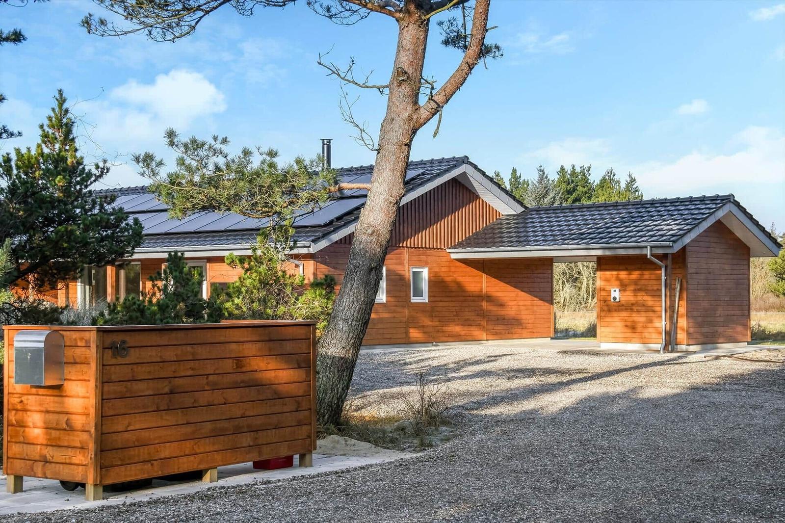 Wooden house with solar panels and tree in front yard