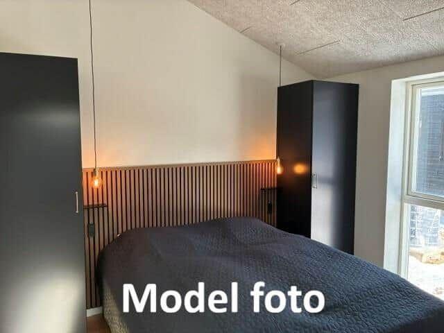 Bedroom with bed, two wardrobes, and wood panels on the wall.