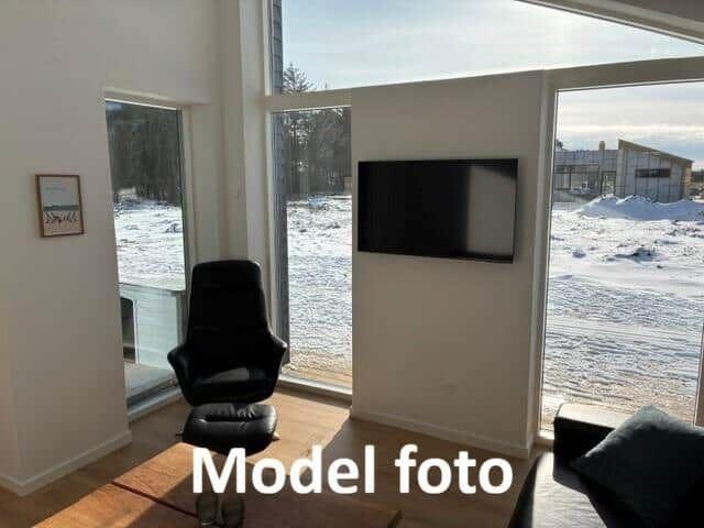 Room with black seating, wall-mounted TV, and large windows for views.