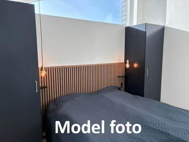 Bedroom with bed, dark cabinets, and wooden wall paneling.