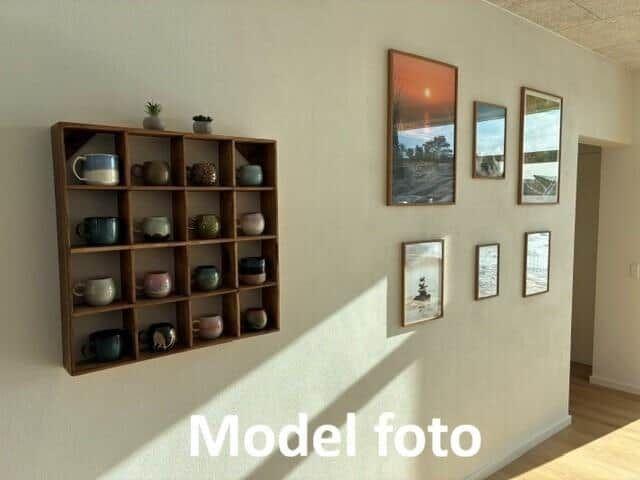 Wall with wooden shelf for mugs and pictures in various sizes.