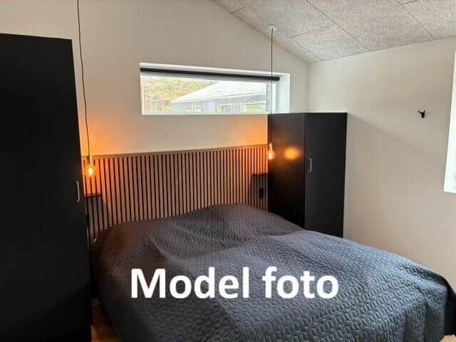 Bedroom with bed, closets, and window. Model photo.