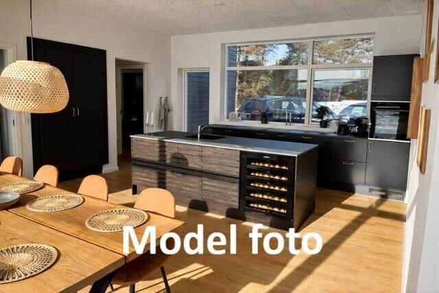 Kitchen with dining area, wooden floor, and large window. Stainless steel countertop and wine rack.