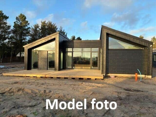 Modern wooden cabin with large windows and terrace in the forest