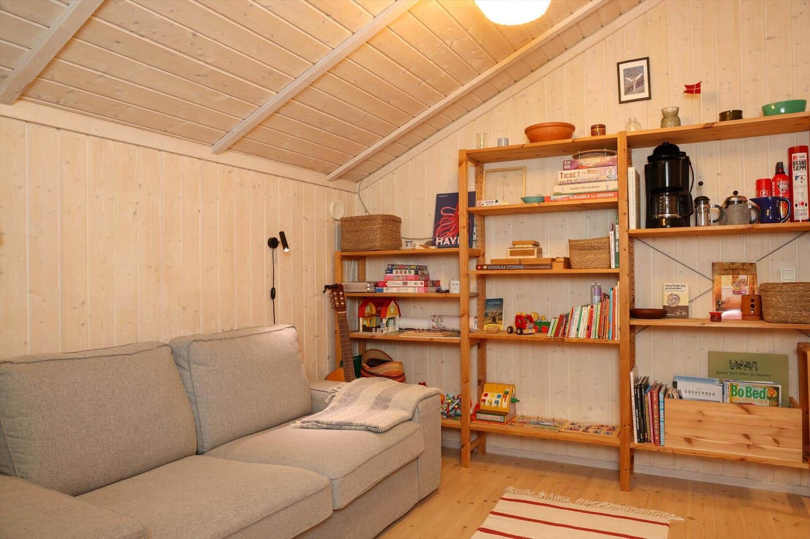 Wohnzimmer mit Sofa, Bücherregal und Holzwand