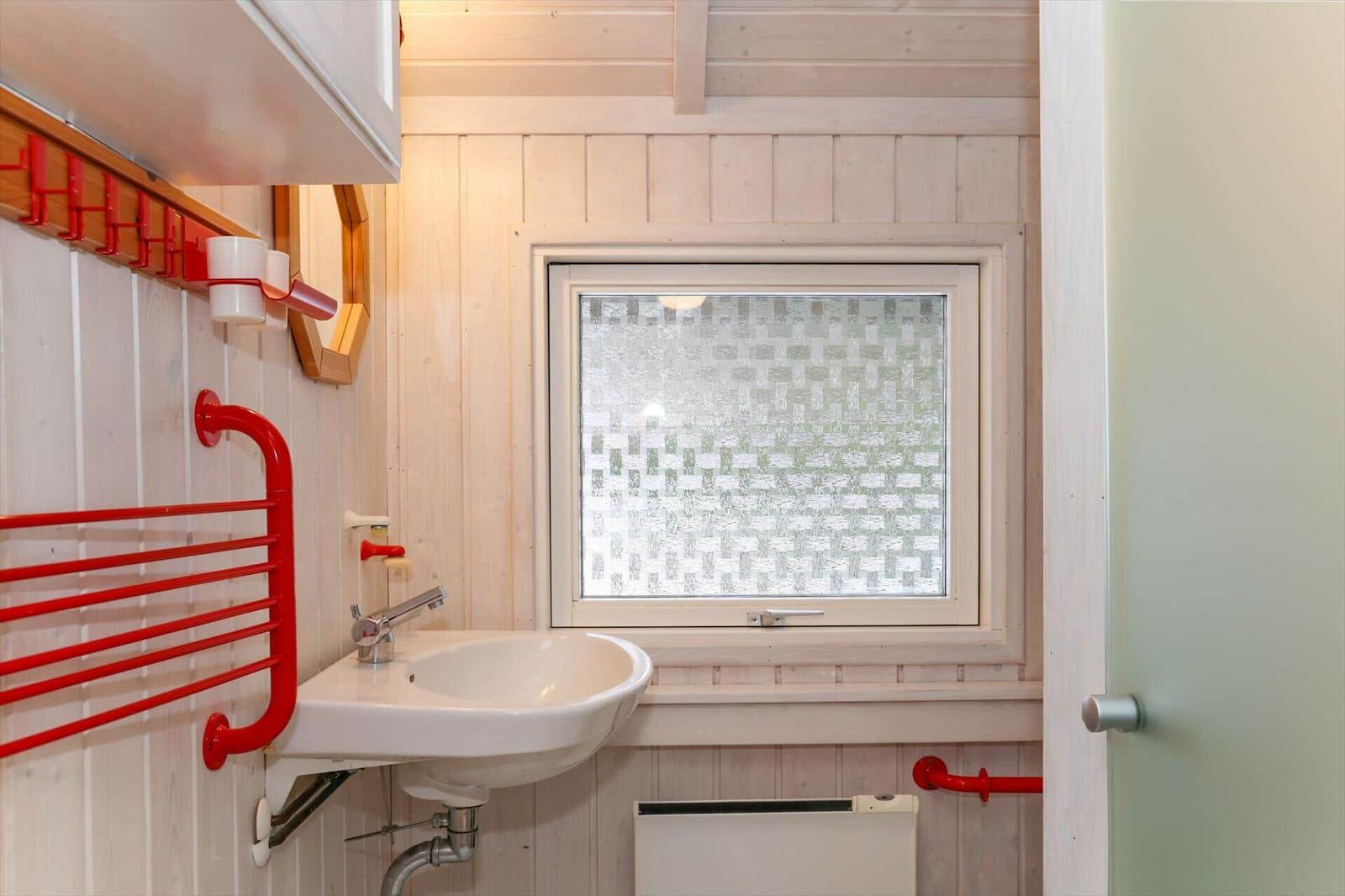 Badezimmer mit Waschbecken, Fenster und rotem Handtuchhalter.