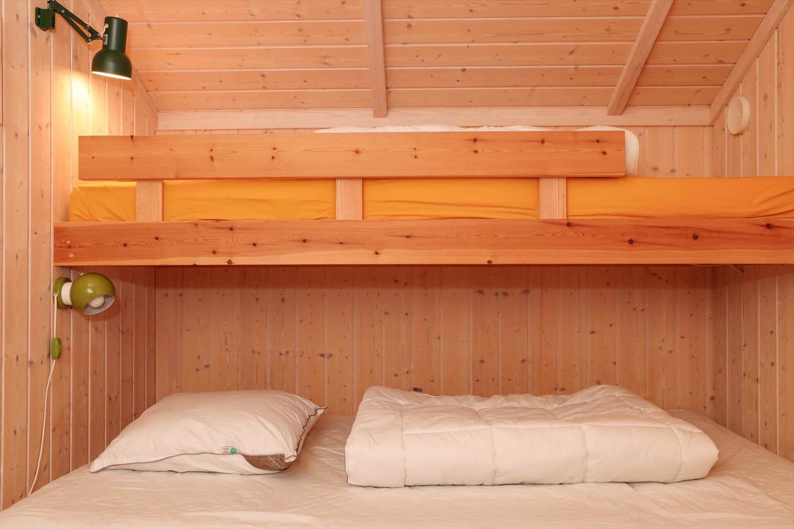 Zimmer mit Doppelbett und oberem Bett mit gelber Bettwäsche.