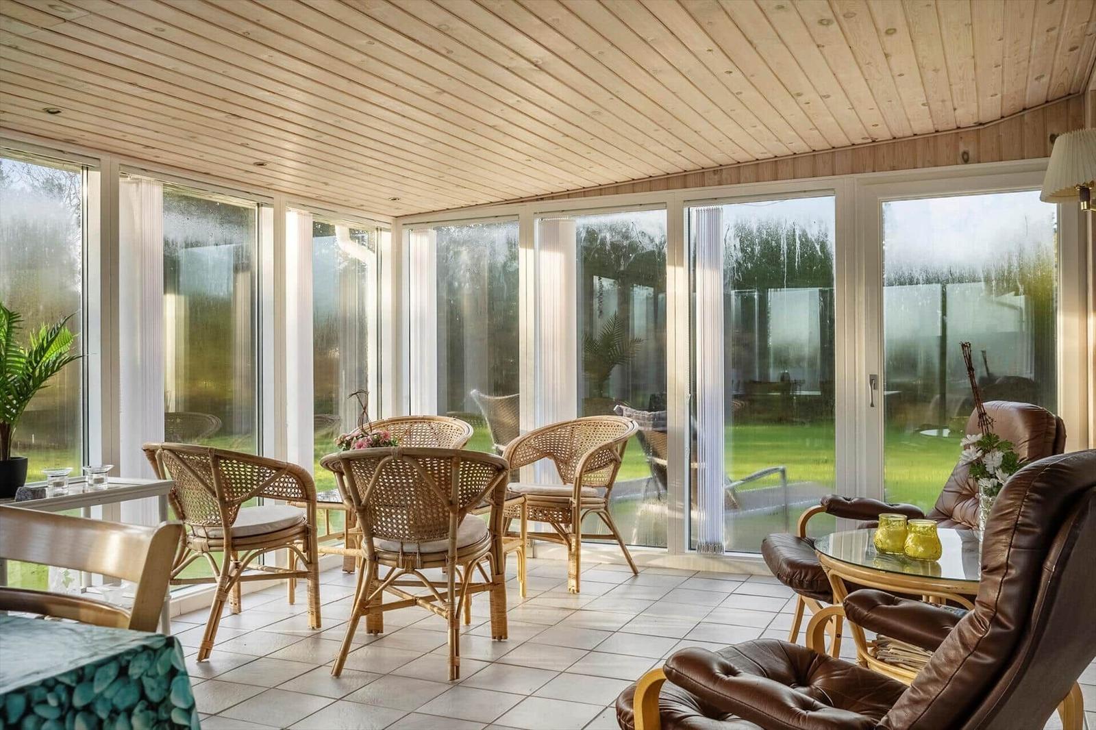 Terrassenbereich mit Sitzgruppe und großflächigen Fenstern zur Außengrünung.
