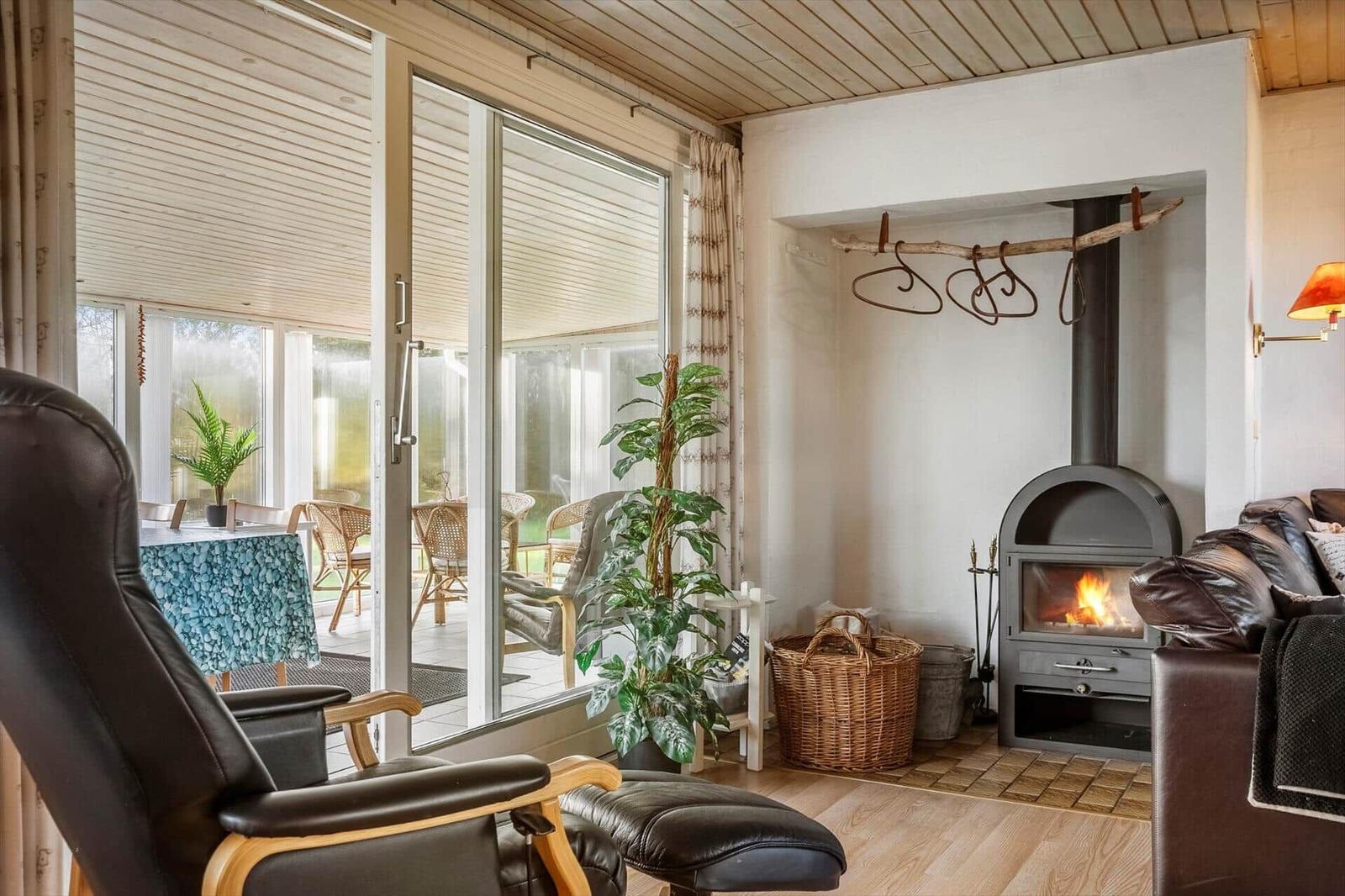 Wohnraum mit Kamin, Sitzgelegenheiten und Blick auf Terrasse.