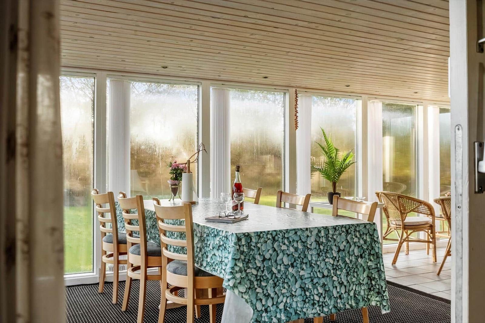 Esszimmer mit Tisch, Stühlen und großen Fenstern zur Aussicht.