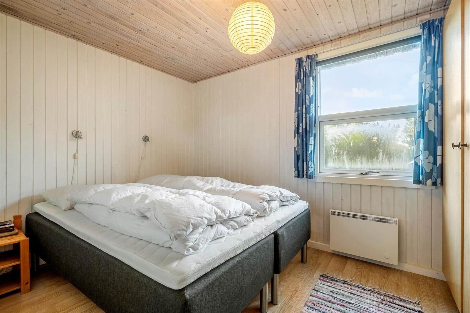 Schlafzimmer mit Bett, Fenster und Holzdecke.