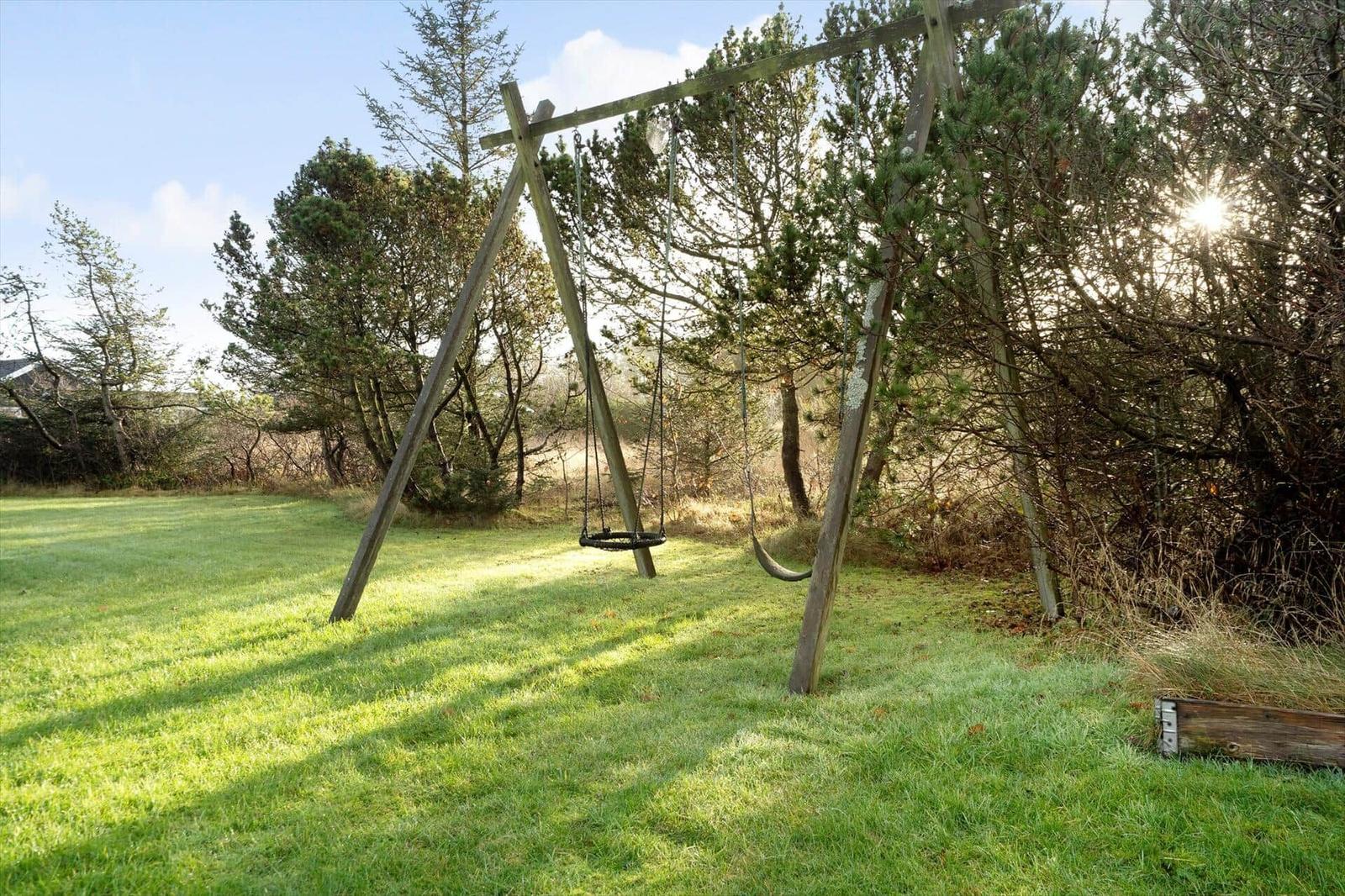 Hinterhof mit Schaukel und Grasfläche unter Bäumen