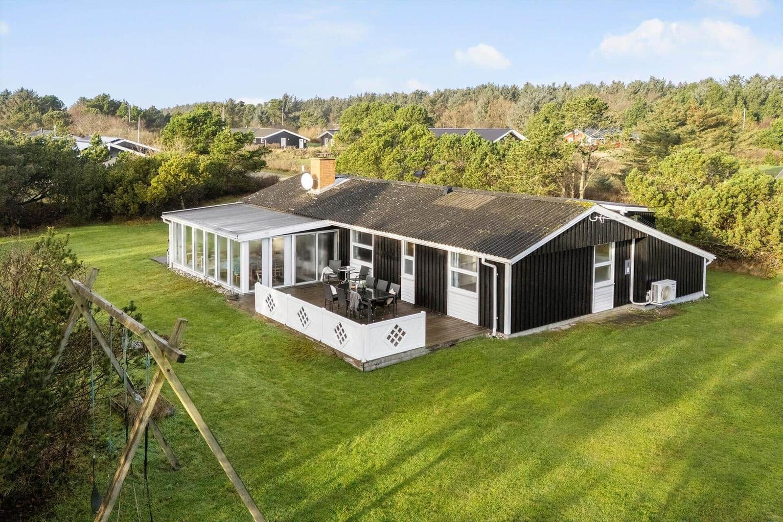 Ein Haus mit Terrasse und Garten. Umgeben von Wald und Grünflächen.