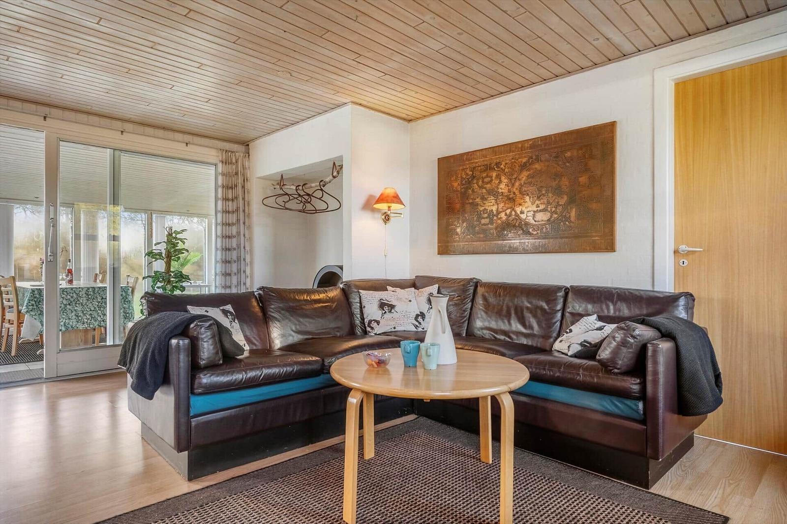 Ein Wohnzimmer mit braunem Ledersofa, Holztisch und Wandbild.