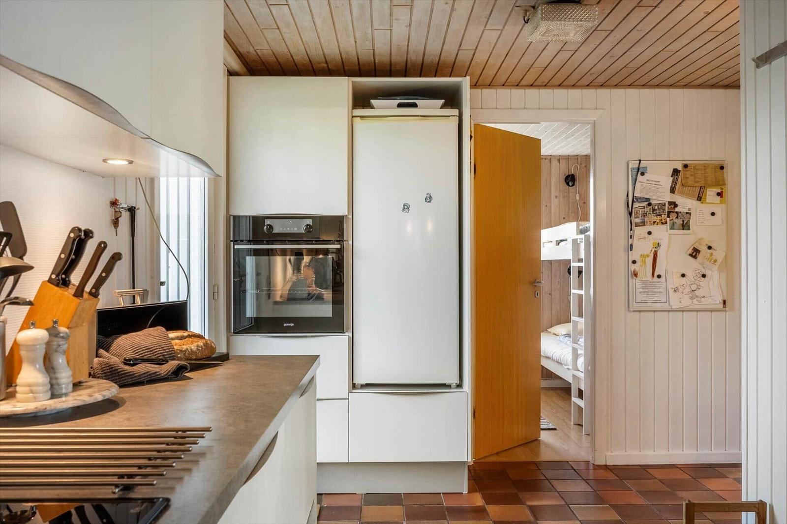 Küche mit integriertem Ofen und Kühlschrank. Durchgang zu Schlafzimmer mit Hochbett.