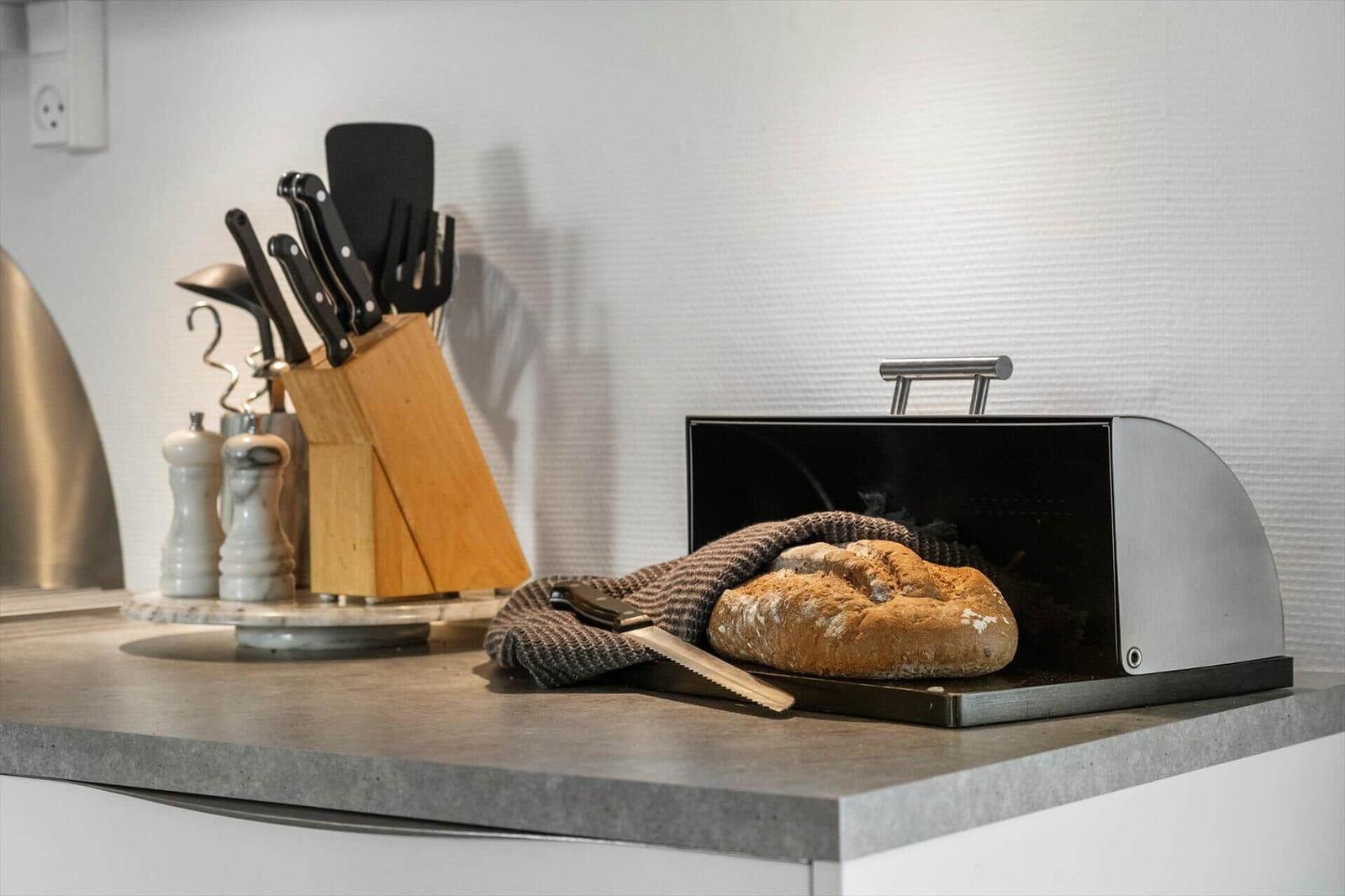 Küchenarbeitsfläche mit Brot, Messer und Küchenutensilien.