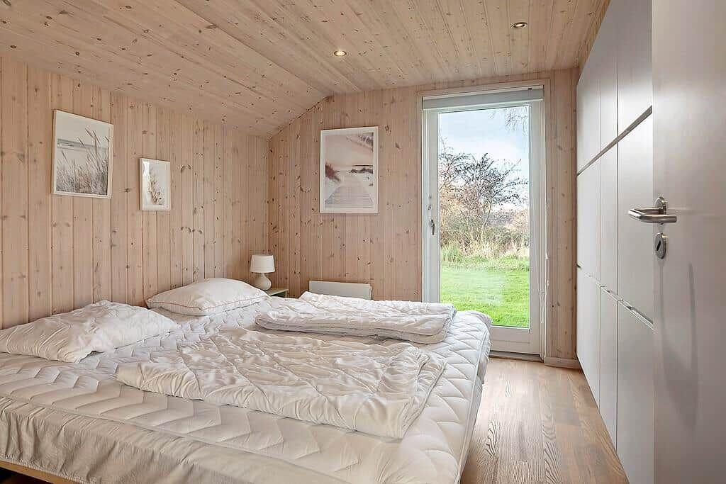 Bedroom with wooden walls, bed, and view of green areas