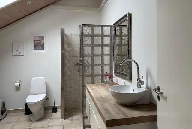 Bathroom with shower, sink and toilet under sloped ceiling
