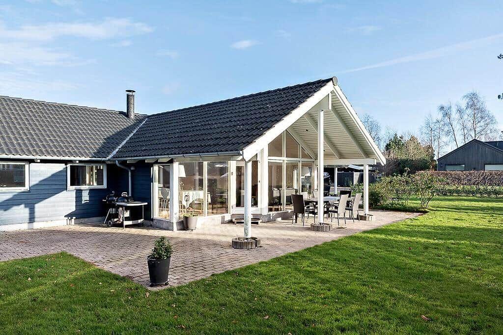 House with terrace, garden, and grill area. Glass veranda with seating.