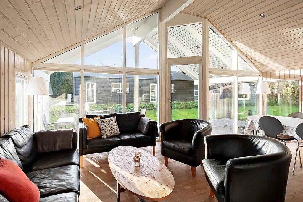 Living room with black leather furniture and large window view of garden