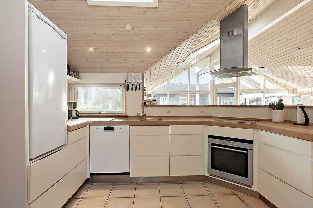 Kitchen with wooden ceiling, windows, and modern appliances.