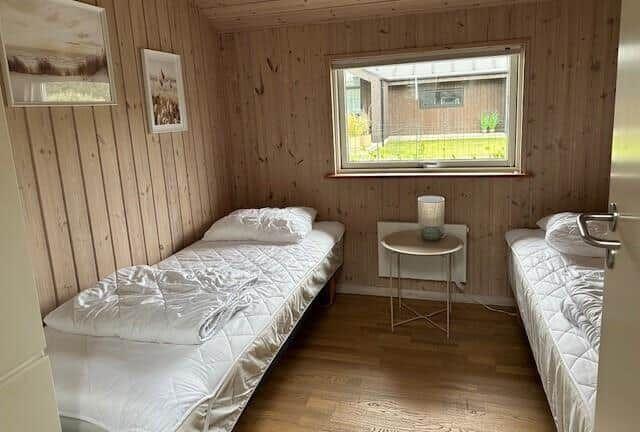 Two single beds, wooden walls, window with view of garden.